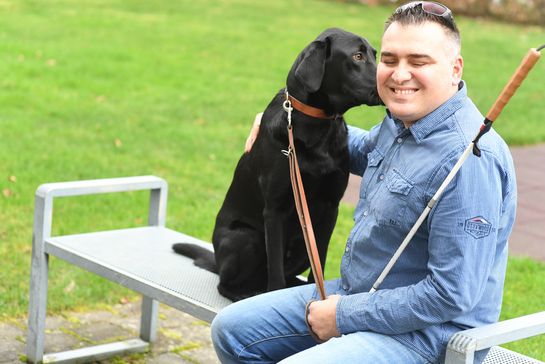 Valentino B. mit seinem Hund Dylan auf einer Parkbank sitzend.