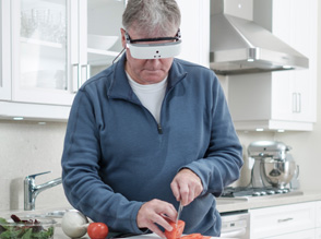 ein Mann schneidet eine Tomate - die esight Brille hilft ihm die Tomate so zu vergrössern, dass er sicher schneiden kann. 