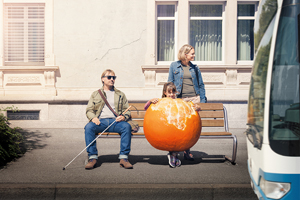 An einer Bushaltestelle wartend nimmt ein Mann mit weissem Stock und Sonnenbrille den Geruch der Mandarine des neben ihm sitzenden Mädchens stark wahr. Die Mandarine ist deshalb überdimensioniert gezeichnet. 
