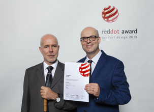 Gerd Bingeman und Stephan Mörker halten die Urkunde für den Red Dot Award in der Hand. Gerd Bingemann trägt am Handgelenk stolz die ACUSTICA Uhr. 