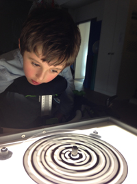 Ein sehbehinderter Junge betrachtet eine Figur in schwarz-weiss auf der beleuchteten Platte der Lightbox.