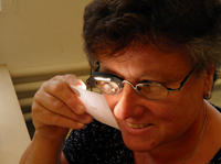 Eine Frau betrachtet mit eingeschalteter Lupenbrillenbeleuchtung einen Text.