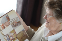 Eine ältere Dame mit Brille betrachtet ihr Fotoalbum.